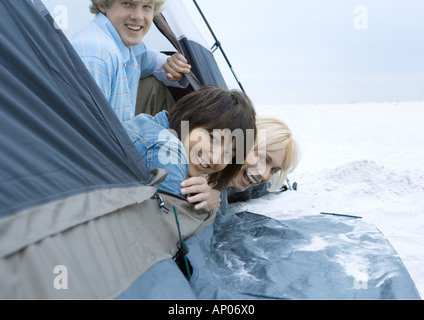 Young adult friends looking out of tent on beach Stock Photo