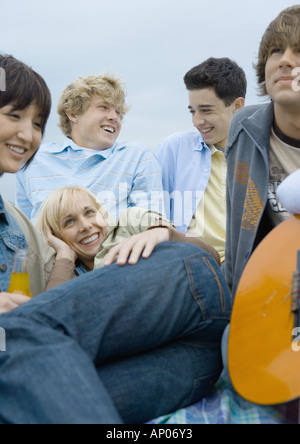 Group of young people sitting together on a day out in public park near ...