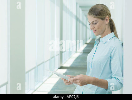 Woman reading document in hallway Stock Photo