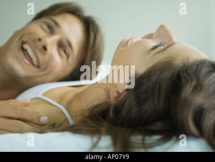 Couple lying in bed together, laughing Stock Photo