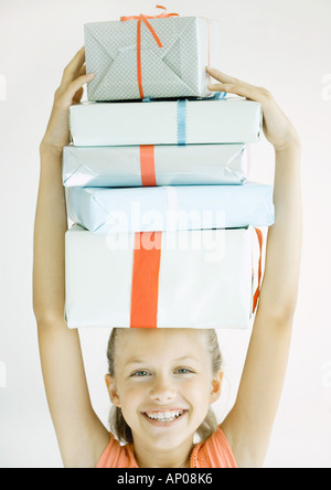 Girl holding stack of presents on head Stock Photo