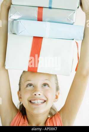 Girl holding stack of presents on head Stock Photo