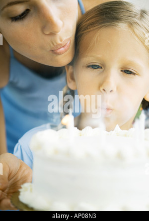 Mother helping daughter blow out birthday candles Stock Photo