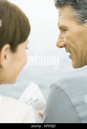 Couple reading newspaper together, water in background Stock Photo