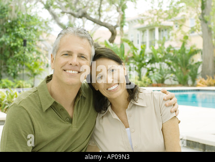 Couple standing in front of pool, smiling Stock Photo