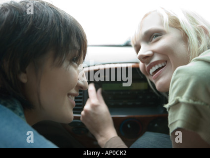 Two female friends in car, one tuning radio Stock Photo