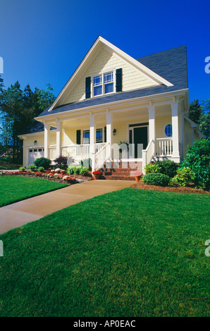 Small Two Story Yellow House with Black Shutters a Porch and Brick Steps Stock Photo