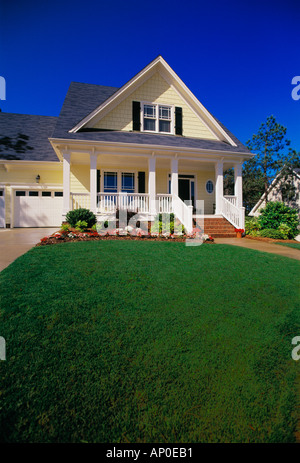 Small Two Story Yellow House with Black Shutters a Porch and Brick Steps Stock Photo