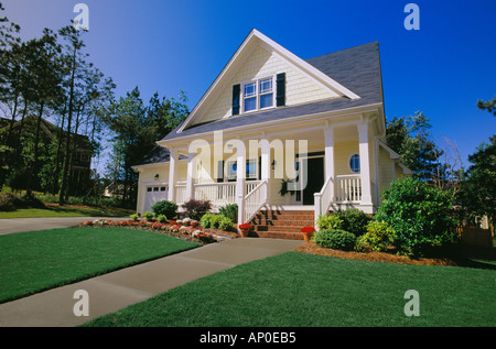 Small Two Story Yellow House with Black Shutters a Porch and Brick Steps Stock Photo