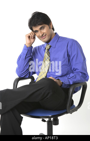 ANG200044 Executive touching his forehead with hand looking into camera and smiling Model release No 687M Stock Photo