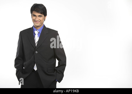 ANG200126 Executive hands in pockets smiling wearing black suit blue shirt and white tie Model release No 687M Stock Photo
