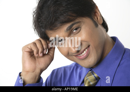 ANG200140 Executive touching his forehead with hand looking into camera and smiling Model release No 687M Stock Photo