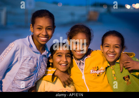 Four girls, friends, standing with arms around each other, dusk, Luxor, Egypt Stock Photo