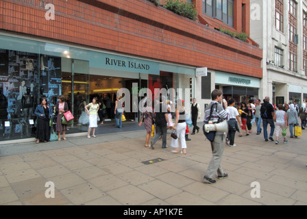 Shoppers on pavement outside store windows River Island clothing shop front & entrance in Oxford Street West End  London shopping street in England UK Stock Photo