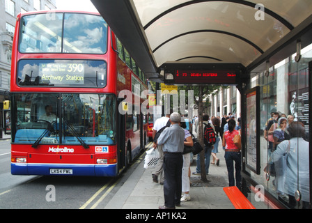 London Oxford Street shoppers number 390 bus at stop with shelter seats and electronic indicator board Stock Photo