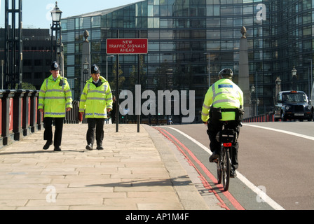 London Lambeth Bridge spanning River Thames 2 two police officers pounding beat on foot being passed by colleague on push bike Stock Photo