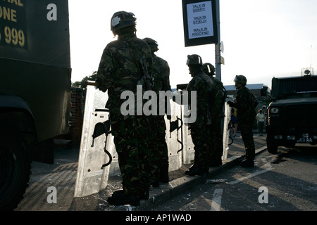 British army soldiers in riot gear with shields backlit silhouette beneath protest sign on crumlin road at ardoyne shops belfast Stock Photo