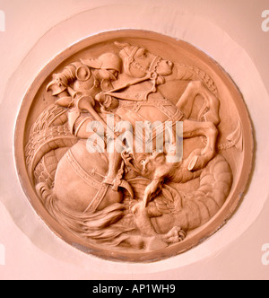 A STONE CARVING SET INTO A WALL DEPICTING SAINT GEORGE SLAYING THE DRAGON UK Stock Photo