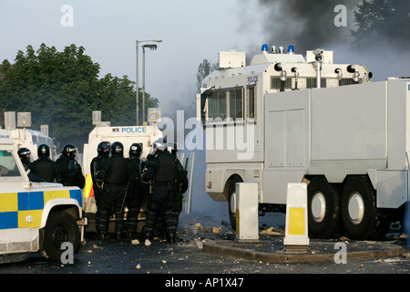 PSNI riot officers behind armoured land rover and water cannon on crumlin road at ardoyne shops belfast 12th July Stock Photo