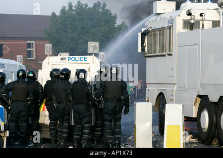 PSNI riot officers behind armoured land rover and water cannon on crumlin road at ardoyne shops belfast 12th July Stock Photo