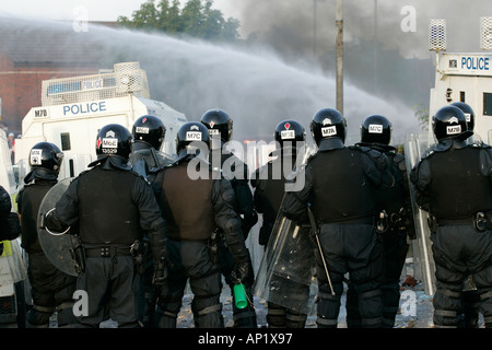 PSNI riot officers behind armoured land rover and water cannon on crumlin road at ardoyne shops belfast 12th July Stock Photo