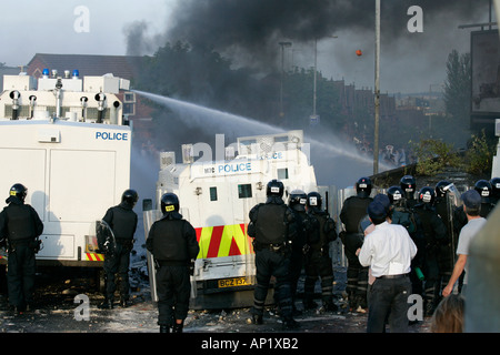 PSNI riot officers behind armoured land rover and water cannon on crumlin road at ardoyne shops belfast 12th July Stock Photo