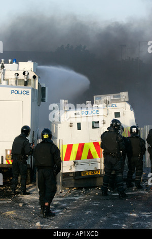 PSNI riot officers behind armoured land rover and water cannon on crumlin road at ardoyne shops belfast 12th July Stock Photo