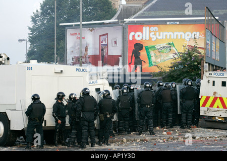 PSNI riot officers behind armoured land rover water cannon beneath on crumlin road at ardoyne shops belfast beneath advertising Stock Photo