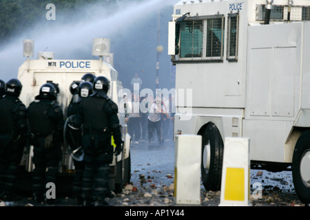 PSNI riot police behind armoured land rover and water canon face on crumlin road at ardoyne shops belfast 12th July Stock Photo