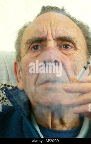 cigarette aging Old age pensioner smoking a cigarette showing signs of long term nicotine  usage with yellowed fingers and wrinkled skin Stock Photo