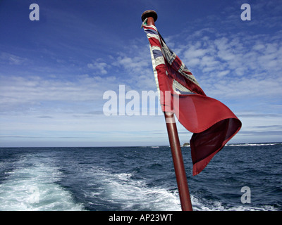 View over the stern of the boat on the way to Tresco, Isles of Scilly, UK, with a Union Jack flag flying from the jackstaff Stock Photo