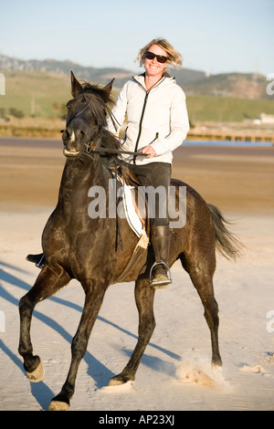 woman riding a horse on the beach Stock Photo