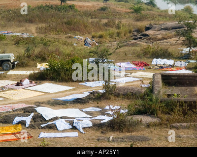 Washing clothes and sheets spread out on ground to dry in countryside beside river Pashwara Madhya Pradesh India Asia Stock Photo