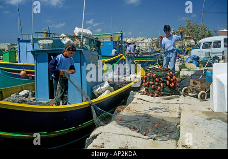 Fishermen with nets and boats in harbour Malta Europe Stock Photo