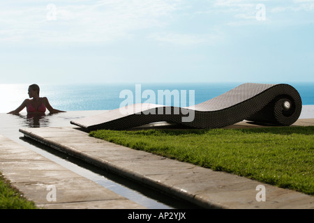 A woman in the swimming pool overlooking the sea, near Uluwatu, Bali, Indonesia Stock Photo