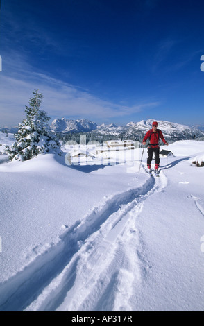 Backcountry skiier in front of deeply snow-covered lodge Straubinger haus with view to Wilder Kaiser range and Unternberghorn, E Stock Photo