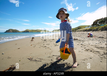 Young girl (2.5 y.) playing at the beach, wearing sun protection swim suit, in front of the tent, campground at Port Jackson on