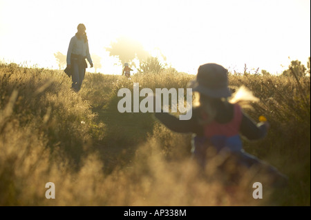 Mother and child wandering through high gras, sunset at the Westcoast, near Haast, South Island, New Zealand Stock Photo
