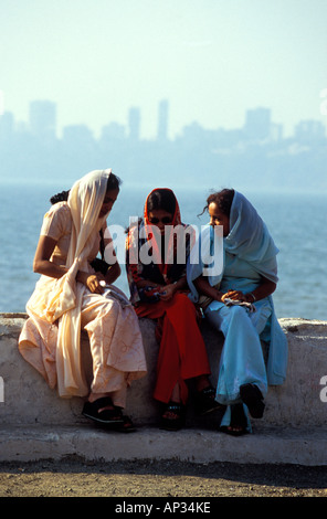 Three veiled Indian women chatting on wall on Marine Drive, Mumbai, South India Stock Photo