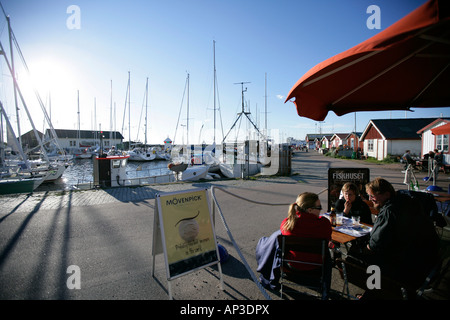 Three people sitting in a cafe at the harbour, Torekov, Skane, Sweden Stock Photo