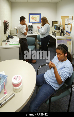 Audiologist confers with Hispanic teen girl s father as her wax ear canal impressions harden prior to fitting a hearing aid Stock Photo