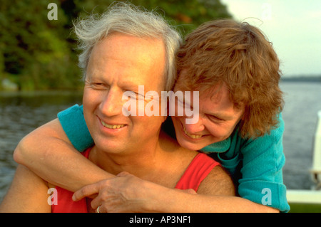 Romantic couple age 55 embracing in motor boat on Sand Lake. Cumberland Wisconsin WI USA Stock Photo