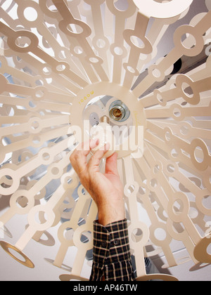 Male hand screwing in energy efficient fluorescent lightbulb in design lamp Stock Photo