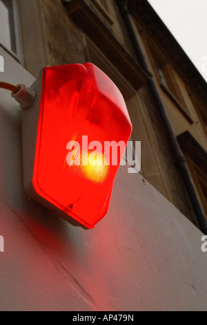 Red security warning light lamp illuminated on side of building Stock Photo