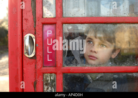 Young boy aged 11 years inside a public telephone call box in winter Stock Photo