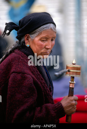 A TIBETAN WOMAN spins her PRAYER WHEEL as she circumambulate the Jokhang Temple along the BARKOR LHASA TIBET Stock Photo