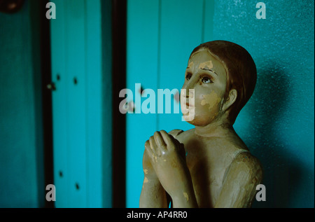 Central America, Nicaragua, Leon. El Convento Hotel. Antique carved figure praying in front of blue wall. Stock Photo