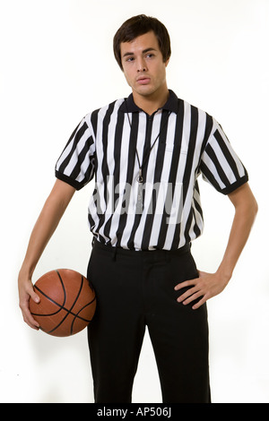 Young brunette man wearing a referee striped black and white top holding a basketball Stock Photo