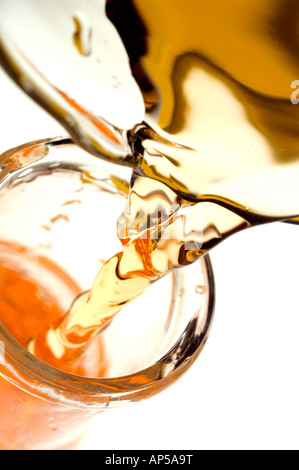 Orange colored liquid pouring from beaker into glass laboratory flask. Stock Photo