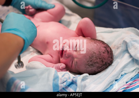 Newborn baby being examined in delivery room Stock Photo